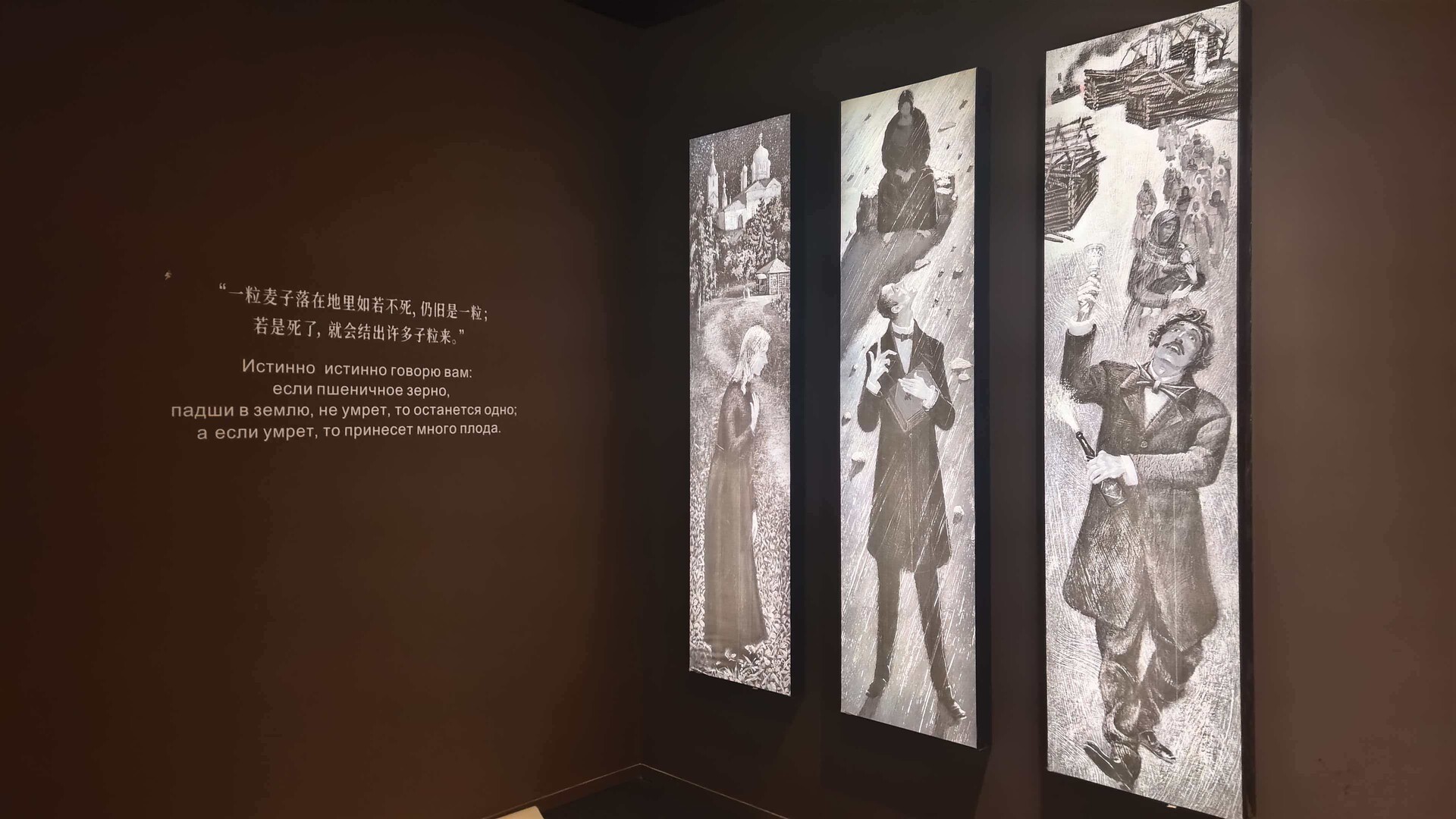 Installation view of “Dostoevsky's World: To Stop Reading Is to Stop Thinking,” showing a dark gallery wall with illuminated black-and-white illustration panels and a bilingual Chinese and Russian quotation about a grain of wheat.